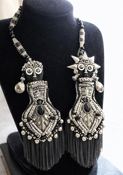 Ornate silver and black beaded earrings on a mannequin bust.